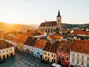 Panoramiczny widok na ośnieżone Alpy austriackie i malowniczą wioskę nad górskim jeziorem o wschodzie słońca.