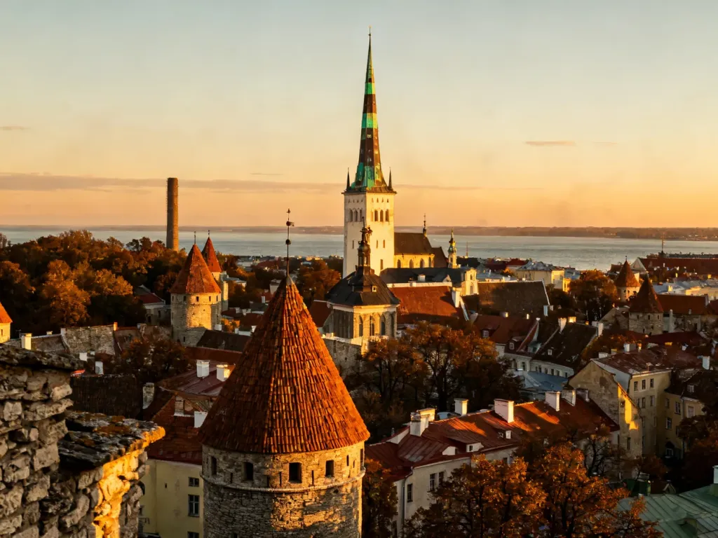 Panoramiczny widok na średniowieczną starówkę Tallinna podczas zachodu słońca z widocznymi wieżami i Zatoką Fińską w tle.