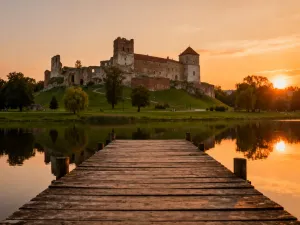 Piaszczysta plaża we Władysławowie z drewnianym pomostem i latarnią morską w tle podczas malowniczego zachodu słońca.