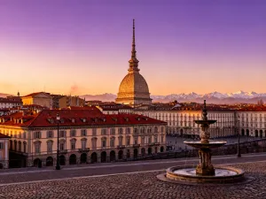 Kolorowe łodzie moliceiros na kanale w Aveiro, z tradycyjnymi zdobieniami i zabytkową architekturą w tle.