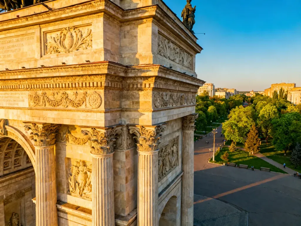 Łuk Triumfalny w Kiszyniowie o zachodzie słońca, otoczony zielenią parku w centrum miasta.