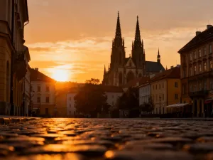 Widok na Stary Port w Marsylii o zachodzie słońca z zacumowanymi łodziami i bazyliką Notre-Dame de la Garde w tle.