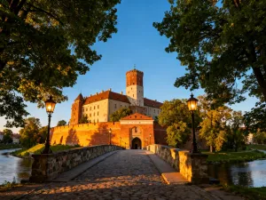 Panoramiczny widok na oświetlone wschodzącym słońcem szczyty Dolomitów oraz kwitnącą alpejską łąkę ze szlakiem turystycznym.