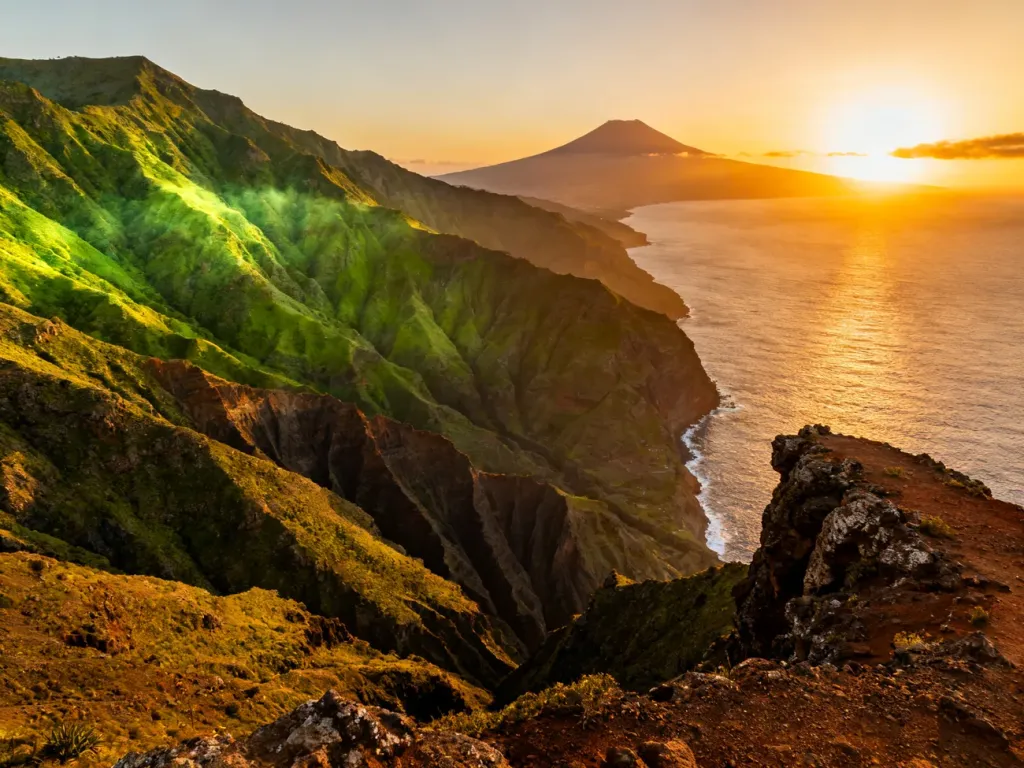 Panoramiczny widok na górzysty krajobraz La Gomery z widocznym w oddali wulkanem Teide podczas zachodu słońca.