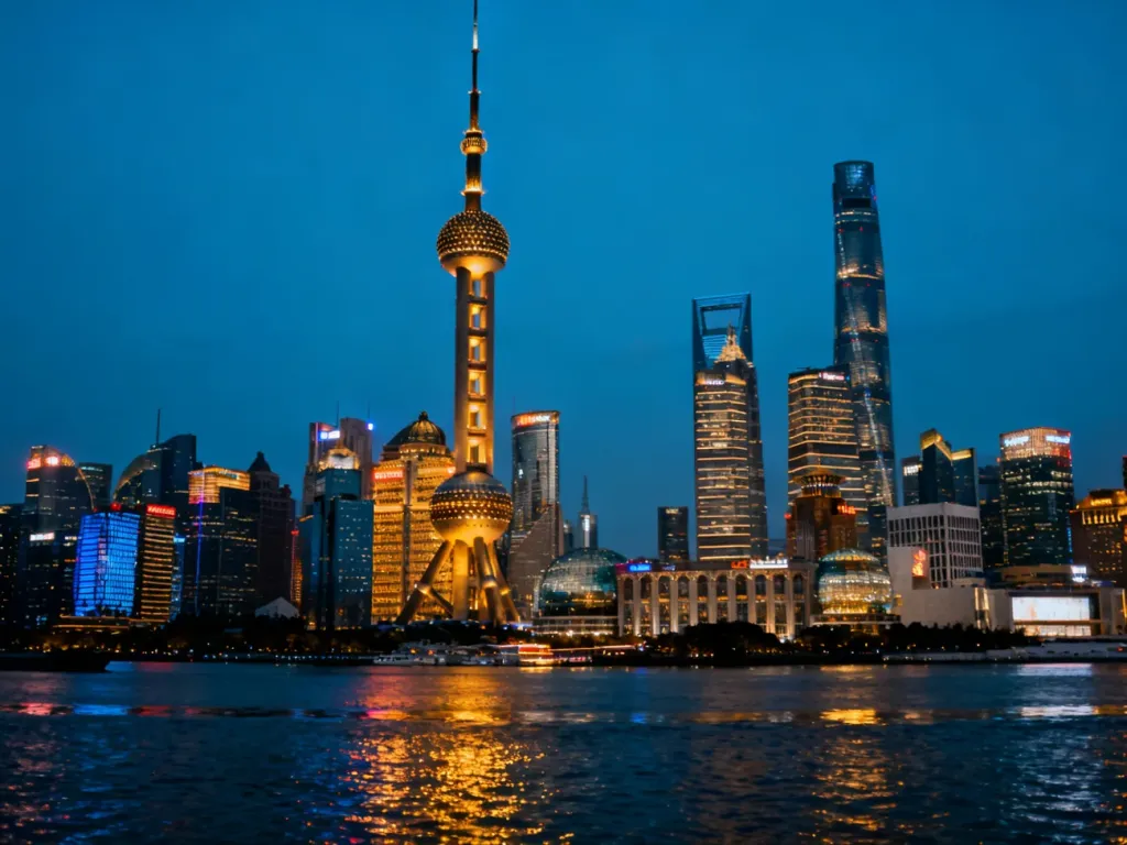 Oświetlona panorama Szanghaju z wieżą Oriental Pearl Tower i rzeką Huangpu o zmierzchu.