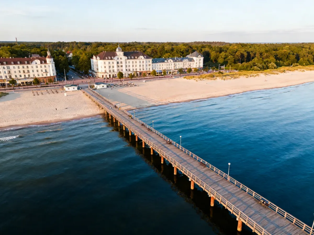 Molo w Międzyzdrojach wychodzące w morze, z plażą i promenadą w tle